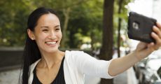 A young happy woman taking a selfie with her smartphone. For beginner's guide to your first filler treatment Dr. Irwin answers on Skintour
