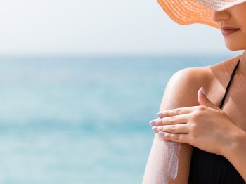 woman wearing hat putting on sunscreen