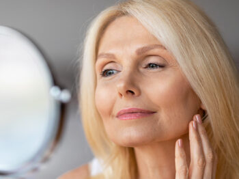 older blonde woman looking into a mirror