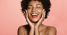 Black woman smiling and hands on both sides of the her face