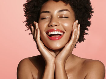 Black woman smiling and hands on both sides of the her face