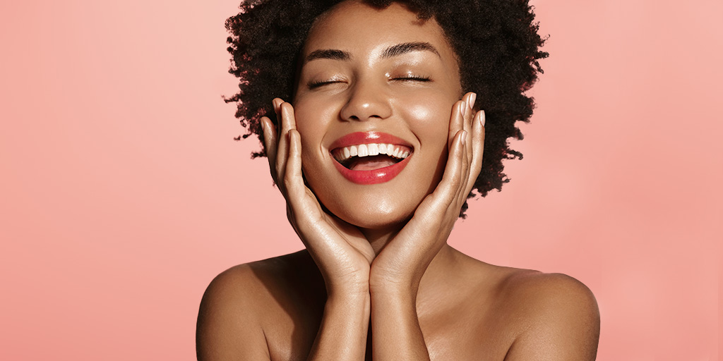 Black woman smiling and hands on both sides of the her face