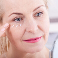 woman applying eye cream in mirror